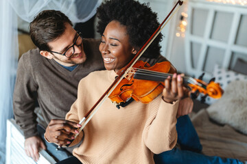 Young beautiful african american woman musician playing violin at home to her love