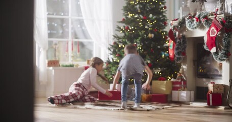 Slow Motion of Happy Little Brother and Sister Waking Up on Holiday Morning to Receive New Toys from Under the Christmas Tree. Cute Children Running Impatiently to Get Their Gifts - Powered by Adobe