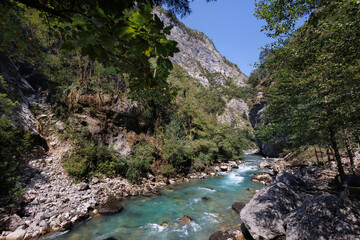 A mountain river with rapids and cliffs on a sunny day