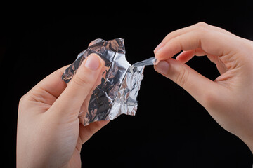 Hand tearing a heart shaped aluminium foil on wooden background