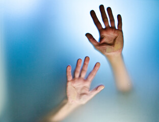 Woman tries to get out and her hands stick up the glass wall she can't get through. The theme is being locked up.
