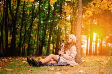 Young attractive girl with clarinet, ebony in fall park