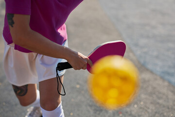 Pickler serving a ball with a racket. Pickleball player practicing outdoors