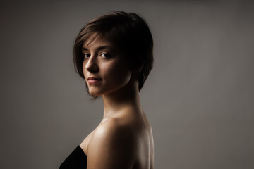 Close up portrait of a beautiful girl. Short hairstyle against gray background.