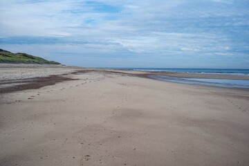 very wide empty sandy beach at low tide in the morning