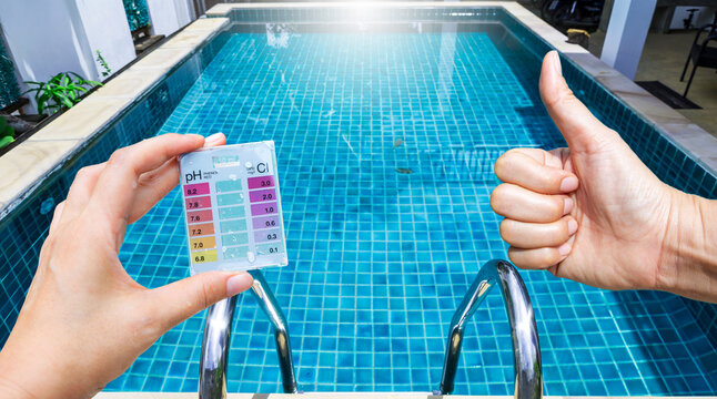 Mini water tester test kit in girl hand over clear swimming pool water, best water quality, pool maintenance, good quality Water testing test kit for swimming pool