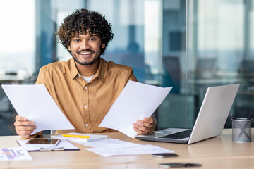 Portrait of young successful financier businessman paper work, hispanic smiling and looking at...