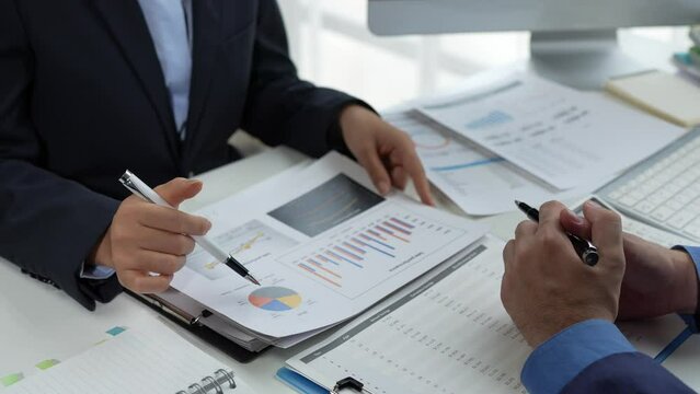 Finance business people or accountants point to the graph and use a calculator to calculate company income, expenses, taxes, and employee bonuses for Next year's improvement plan