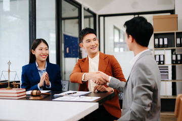 Man lawyer hand and women client shaking hand collaborate on working agreements with contract documents at the office..