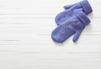 purple  mittens on white wooden background