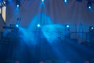 music stage is illuminated by spotlights at night, illuminated with blue lights music scene at a...