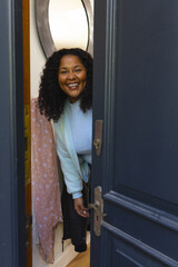 Happy african american woman opening door and smiling on sunny day