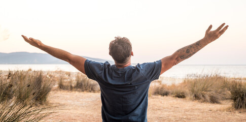 Happiness and freedom travel people lifestyle. One man back view outstretching arms overjoy and...