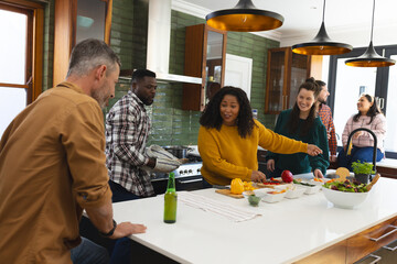 Happy diverse male and female friends preparing meal in kitchen