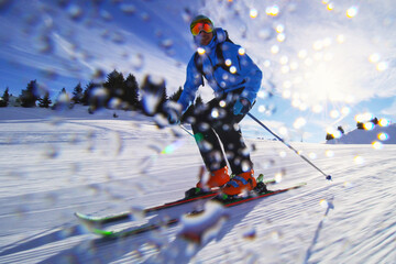 Professional skier skiing on slopes in the Swiss alps and throwing snow at the camera. Water drops...