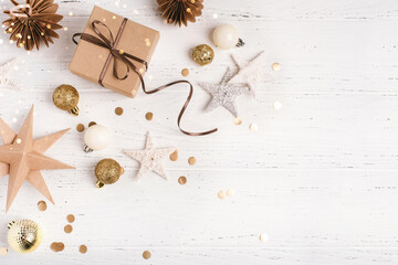 Festive Christmas background with gift box and Christmas decorations on white wooden table. Top...