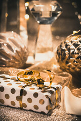 Close-up of gift, baubles and decoration on a table decorated for Christmas, warm gold colors,...