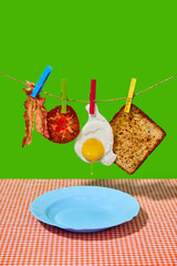 Ingredients. Fried egg, bacon, tomato and sandwich hanging over plate on green background. Concept of breakfast, food, taste, health, creativity. Pop art photography. Poster. Copy space for ad