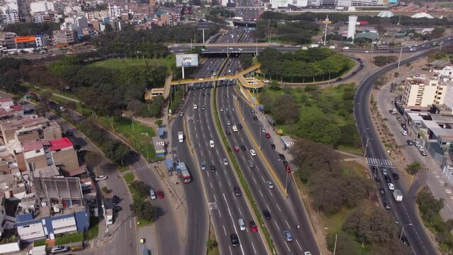 Drone footage of a cloverleaf interchange called "Trebol Javier Prado". Camera slowly pans up to see the long street called "Javier Prado".  Located in Lima, Peru.