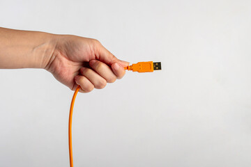 Hand and usb cable isolated on orange background 