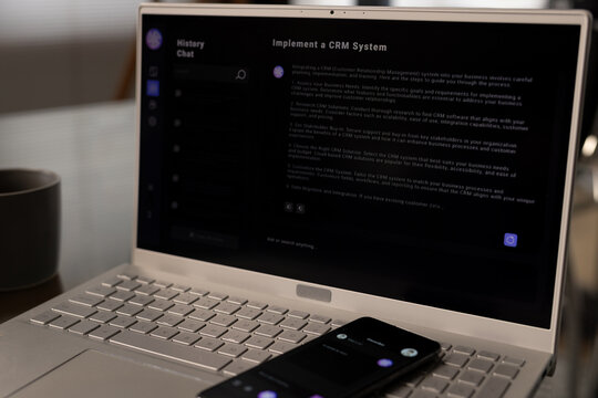 Laptop on desk and smartphone on keyboard with web chat on both screens at home office
