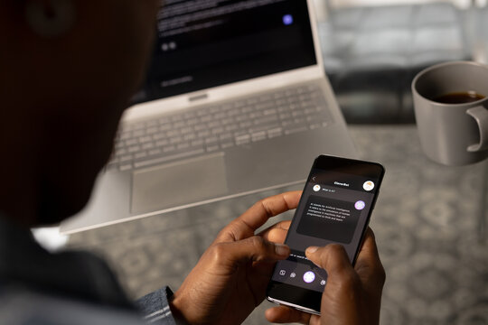 African american casual businessman laptop and holding smartphone with web chat on screen