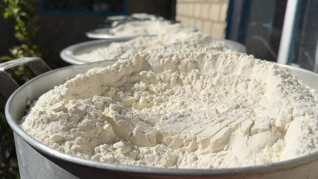 white flour in metal containers is prepared for further packaging