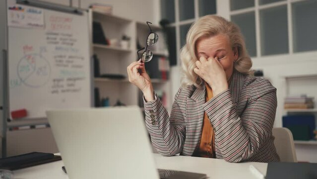 Tired middle-aged businesswoman feeling eye tension while working on laptop