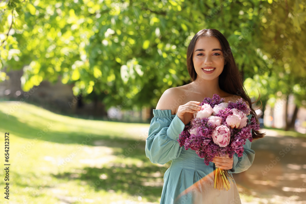 Poster Beautiful woman with bouquet of spring flowers in park on sunny day, space for text