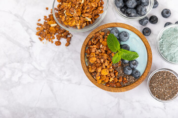 Granola bowl. Yogurt with oatmeal, fresh berries, spirulina and chia seeds. Healthly food. Tasty breakfast. Yogurt with strawberries, raspberries, blueberries, peaches, mint and mendal. Copy space.