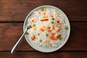 Delicious rice with vegetables on wooden table, top view