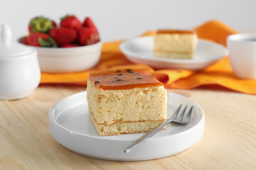 Piece of cheesecake with jelly and fork on wooden table