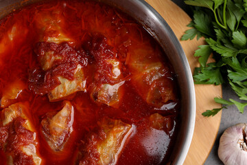 Delicious stuffed cabbage rolls cooked with homemade tomato sauce in pot on table, top view