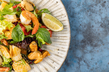 salad with mussels, shrimp, lime on a gray-blue background. Place for text.