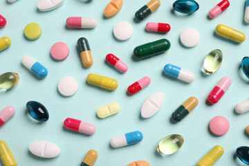 Many different pills on light turquoise background, flat lay
