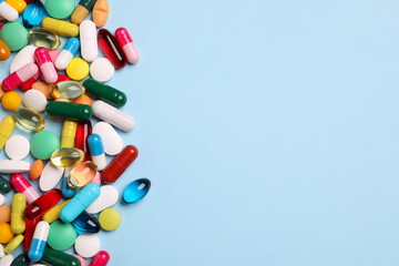 Many different pills on light blue background, flat lay. Space for text