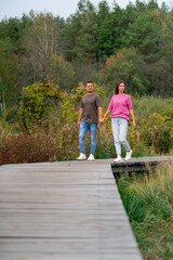 young married couple man and woman walking through the forest holding hands and enjoying beauty of nature