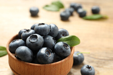 Bowl of tasty fresh blueberries on wooden table, closeup. Space for text