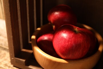 Fresh red apples in bowl on wooden table, closeup