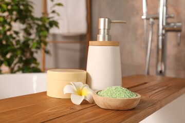 Spa products and beautiful plumeria flower on wooden tub tray in bathroom