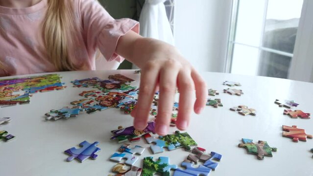 Little child picks up picture from pieces of puzzles	