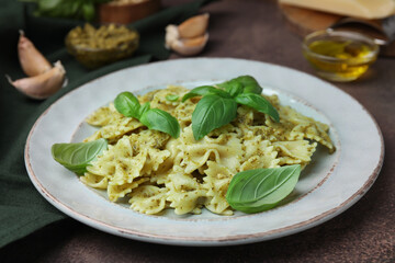 Delicious pasta with pesto sauce and basil on table, closeup
