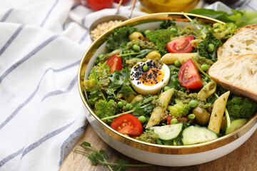 Delicious salad with pesto sauce in bowl on table, closeup. Space for text