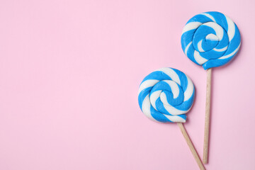Sticks with bright lollipops on pink background, flat lay. Space for text