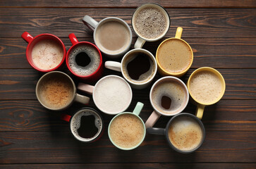 Many different cups with aromatic coffee on wooden table, flat lay