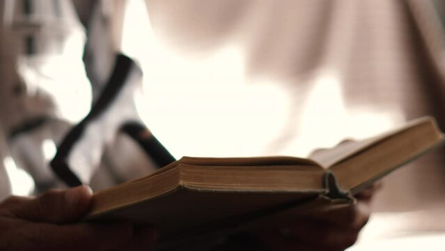 A Pensioner 70-79 Years Old Reads A Book While Sitting With A Walking Cane. Selective Focus. Leisure Time For Older People. Old Man Reading Old Bible Book