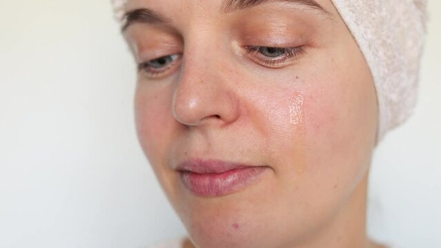 Closeup of attractive woman using beauty product applying nourishing anti-aging moisturizing serum on her face in the morning isolated over white background.