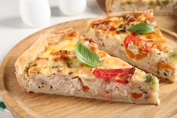 Tasty quiche with chicken, vegetables, basil and cheese on white table, closeup