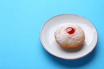 Hanukkah donut with jelly and powdered sugar on turquoise background, space for text