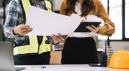 Businessman working as a team discussing data working and tablet, laptop with on on architectural project at construction site at desk in office.